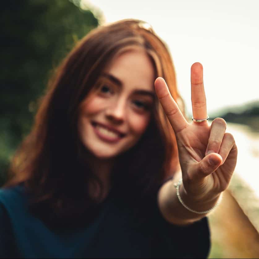 Smiling Woman Peace Handsign Representing Enneatype 9